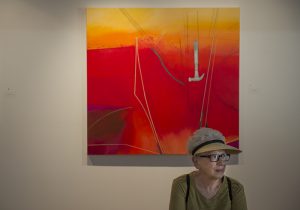 Judy Duchan sits in front of "Monday" by Virginia Sharkey during the 59th Chautauqua Annual Exhibition of Contemporary Art during the opening reception in Strohl Art Center on Sunday, June 26, 2016.