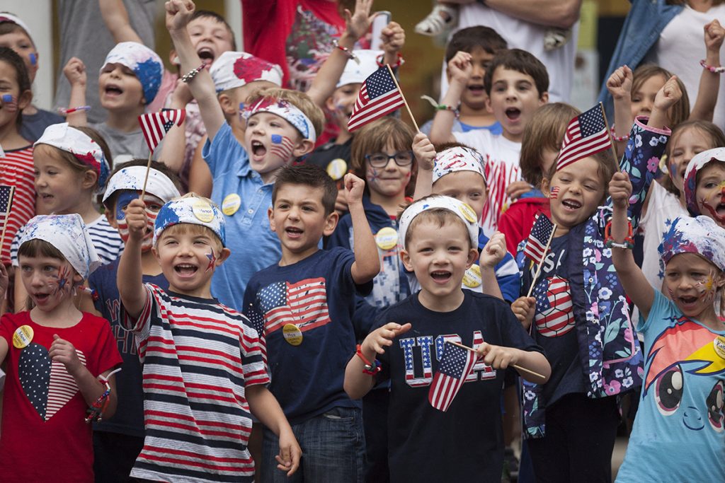 Children sing patriotic songs on the steps of the Colonnade at the conclusion of Children's School's annual Independence Day Parade on July 1, 2016. The parade was held on the Friday before the Fourth of July because the holiday officially falls on a Monday, which would give newcomers to Children's School no time to prepare for the parade. The parade was almost relocated due to rain, but the skies cleared up enough for the children to march to the Colonnade along their traditional parade route. Photo by Carolyn Brown.