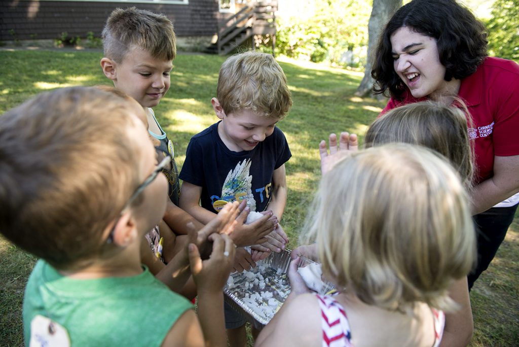Children gather around Aly Toy from the Carnegie Science Center as they felt some puddy made out of powder and water during a presentation about outer space at Children's School on July 21, 2016. Photo by Sarah Holm