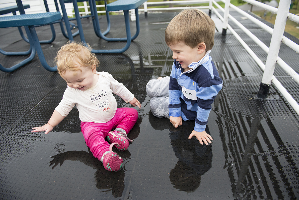 Graham Lockwood, 3, and Posey Wannop, 13 months, play in a puddle during the the 2016 Summer Fest sponsored by the NOW Generation on July 30, 2016 in the Youth Activities Center. Photo by Sarah Holm
