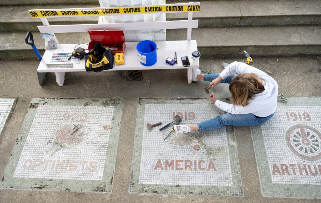 Denise Stebbins of Living Glass Gallery in Westfield, New York, works April 16 to remove damaged tiles from two mosaics in the Hall of Philosophy. 
