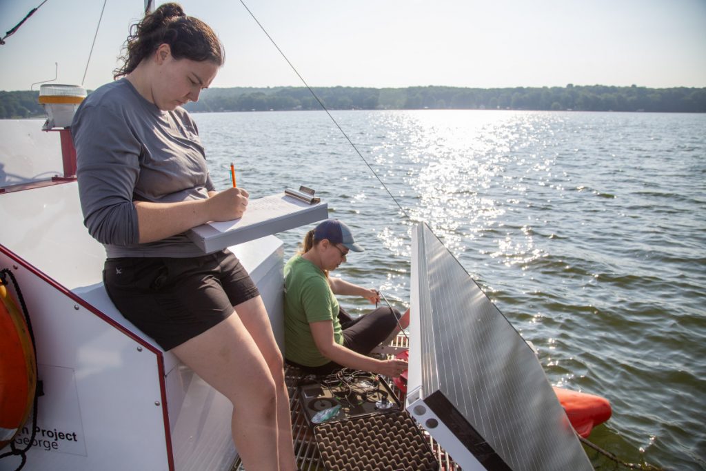 Kira Yerofeev, research specialist with Rensselaer Polytechnic Institute, takes notes as Allison Hyrcik measures the water depth before taking samples on Aug. 12 on Chautauqua Lake.